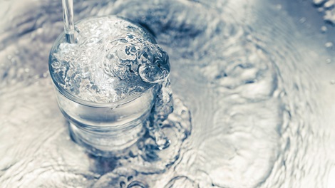 Klar frisk vand der løber ned i et glas